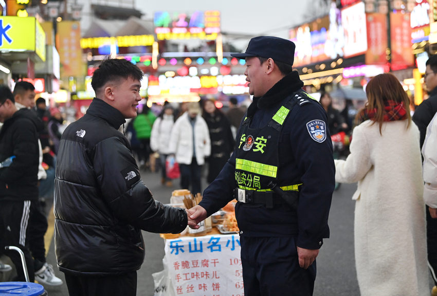 被幫助的游客和樂(lè)山市公安局市中區(qū)分局張公橋派出所副所長(zhǎng)白科翔握手，表示感謝。樂(lè)山公安供圖